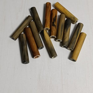 May include: A collection of 12 wooden dowels in various shades of brown and black. The dowels are approximately 7.5 cm long and have a smooth, polished finish.