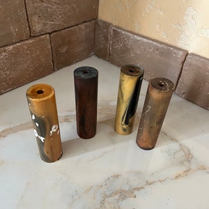 May include: Four different coloured cylindrical pen blanks. The blanks are made of a marbled material with brown, black, white, and gold colours.