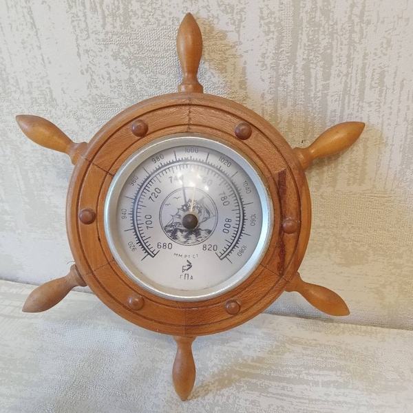 Round wooden barometer in a nautical style. Meteorological instrument. Weather station. Wooden steering wheel. Vintage wall decor.