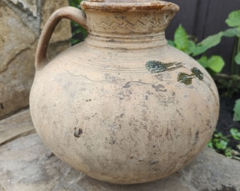 Antique earthenware vessel with a brown handle. Pot. Ancient water jug. Fragment of clay Ukrainian dishes of the 1940s.