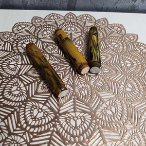 May include: Three yellow and black patterned fountain pen cartridges on a white surface with a gold-coloured decorative design.