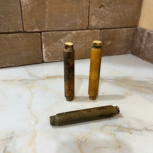 May include: Three wooden dowels, two are brown and one is light brown. The dowels are on a white marble surface.