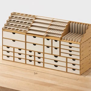 May include: A wooden craft organizer with multiple drawers, shelves, and compartments. The organizer is 1 meter long, 25 cm deep, and 55 cm tall. It features a natural wood finish with white drawer fronts and is designed for storing various art supplies.
