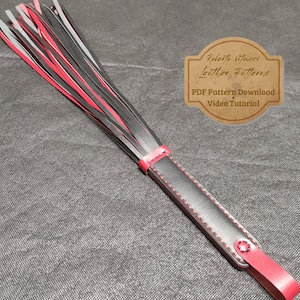 May include: A black and red leather whip with a black handle and red stitching. The whip has a fringe of black and red leather strips. The image includes the text "Roberto Vitucci Leather Patterns" and "PDF Pattern Download + Video Tutorial".