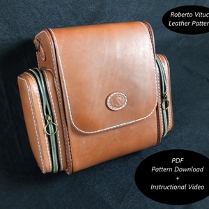 May include: A brown leather bag with two zippered compartments and a white stitching detail. The bag has a small circular logo with a horse and rider design. The text "Roberto Vitucci Leather Patterns" is visible at the top of the image. The text "PDF Pattern Download + Instructional Video" is visible at the bottom of the image.