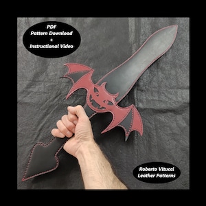 May include: A black leather sword with a red bat design. The sword has a stitched edge and a grinning bat face. The text "PDF Pattern Download + Instructional Video" is at the top of the image. The text "Roberto Vitucci Leather Patterns" is at the bottom of the image.