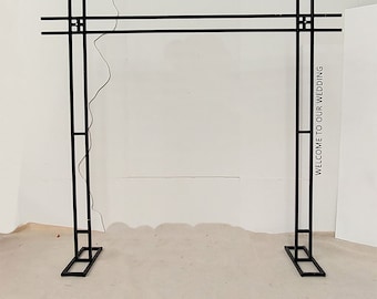 May include: A black metal wedding arch with the text "Welcome to our wedding" on the right side and "Come to our wedding" in Chinese on the left side.