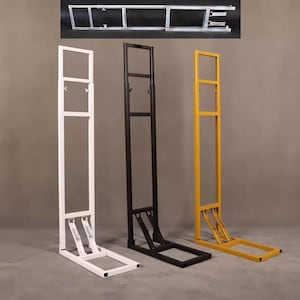 Puede incluir: Tres expositores metálicos en blanco, negro y amarillo. Cada soporte tiene una base rectangular y un marco alto y abierto. Los soportes están diseñados para sujetar y exhibir artículos. Un cuarto soporte desmontado se muestra en la parte superior.