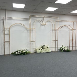 光沢のあるゴールドの背景スタンド 結婚式用の金色のスチールアーチ セレモニーステージレイアウト トラスの背景 アーチ装飾