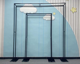 May include: Two black metal archways, one larger than the other, stand against a blue wall with a white and gray striped pattern. The wall has a whimsical design with white clouds and yellow stars.
