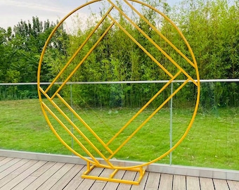 May include: A gold metal circular arch with a geometric diamond pattern. The arch is freestanding and has a base.