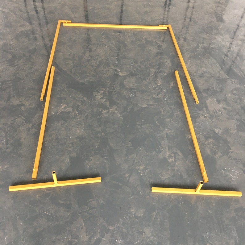 May include: A gold metal archway kit, disassembled, with four pieces. The archway is made of thin metal tubing and is designed to be assembled into a rectangular shape.