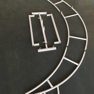 May include: A set of white metal archway pieces for a backdrop or photo booth. The pieces are made of lightweight metal tubing and connect together with clips. The archway is designed to be curved and can be assembled into a variety of shapes.