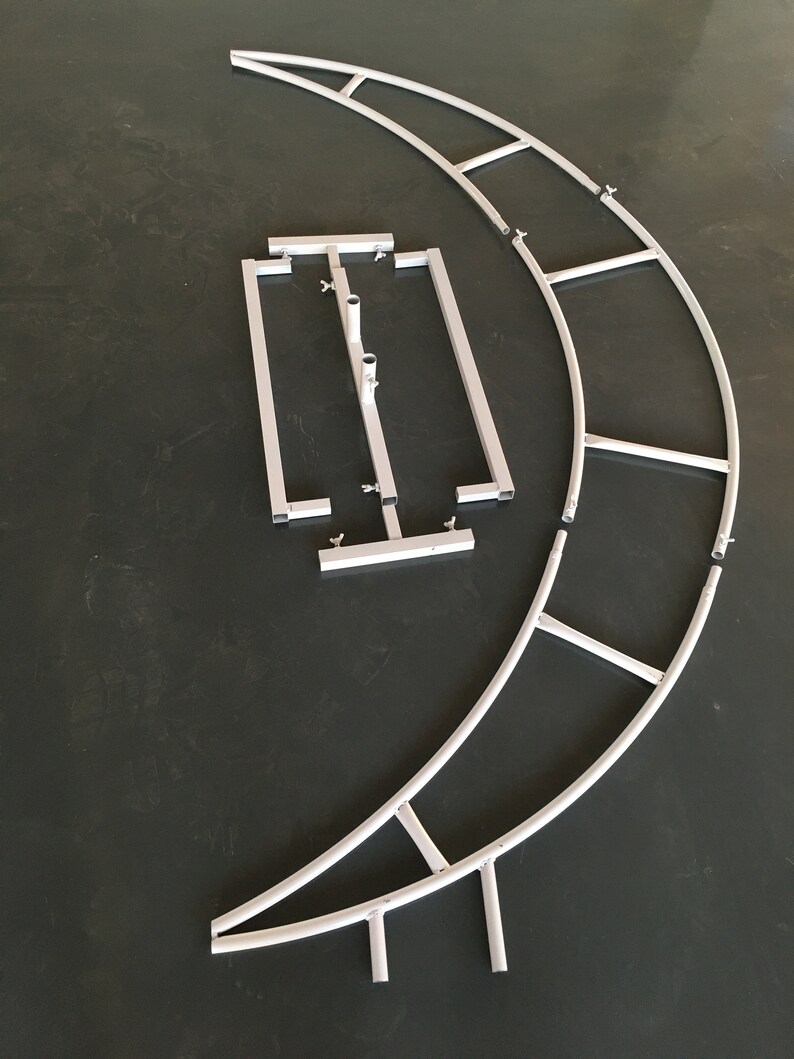 May include: A set of white metal archway pieces for a backdrop or photo booth. The pieces are made of lightweight metal tubing and connect together with clips. The archway is designed to be curved and can be assembled into a variety of shapes.