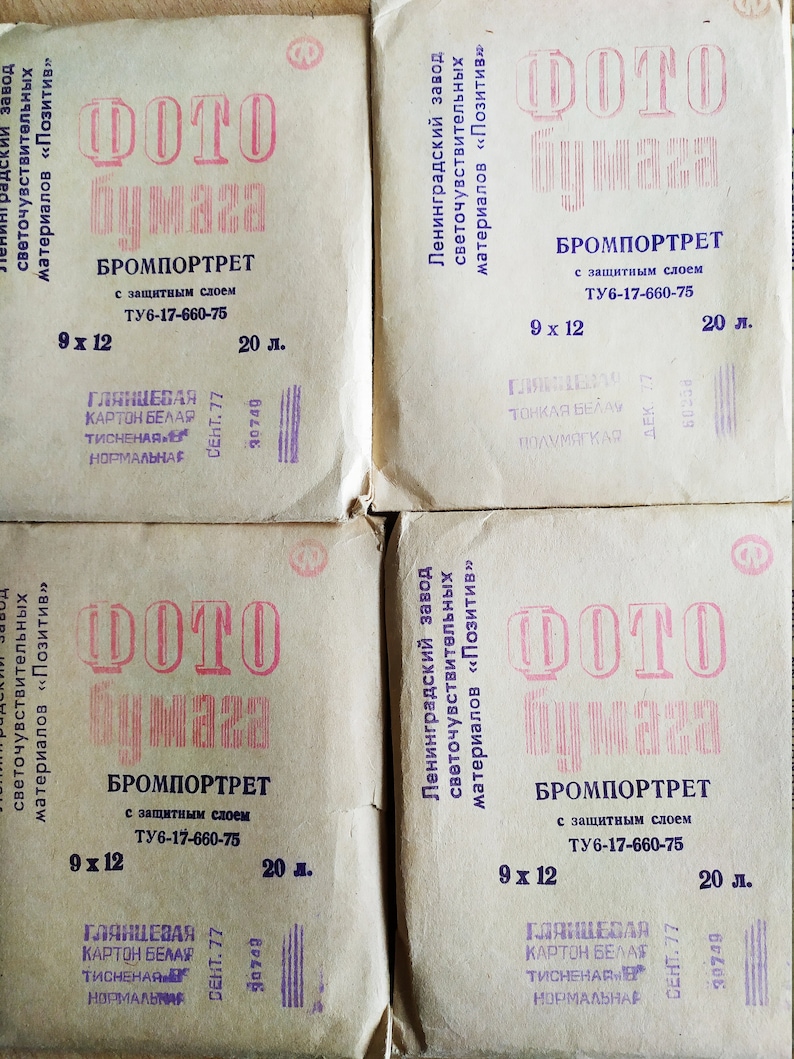 Może przedstawiać: Cztery opakowania papieru fotograficznego w stylu vintage. Każde opakowanie jest beżowe z czerwonym tekstem, kt&oacute;ry brzmi "Papier fotograficzny Bromportrait" i innym tekstem cyrylicy. Opakowania są oznaczone 9 x 12 i 20 l.