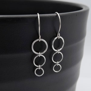 May include: Silver dangle earrings with four connected circles.