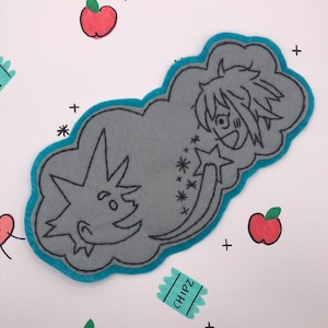 May include: A gray felt patch with a blue border, featuring cartoon characters and stars. The patch is surrounded by drawings of apples, hearts, and the word "CHIPZ" on a teal rectangle, all on a white background.