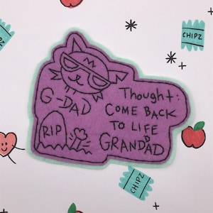 May include: A purple felt patch with a cat wearing sunglasses and the words "G-DAD RIP GRANDAD Thought: COME BACK TO LIFE". The image also includes drawings of apples, hearts, and "CHIPZ" snack packets.