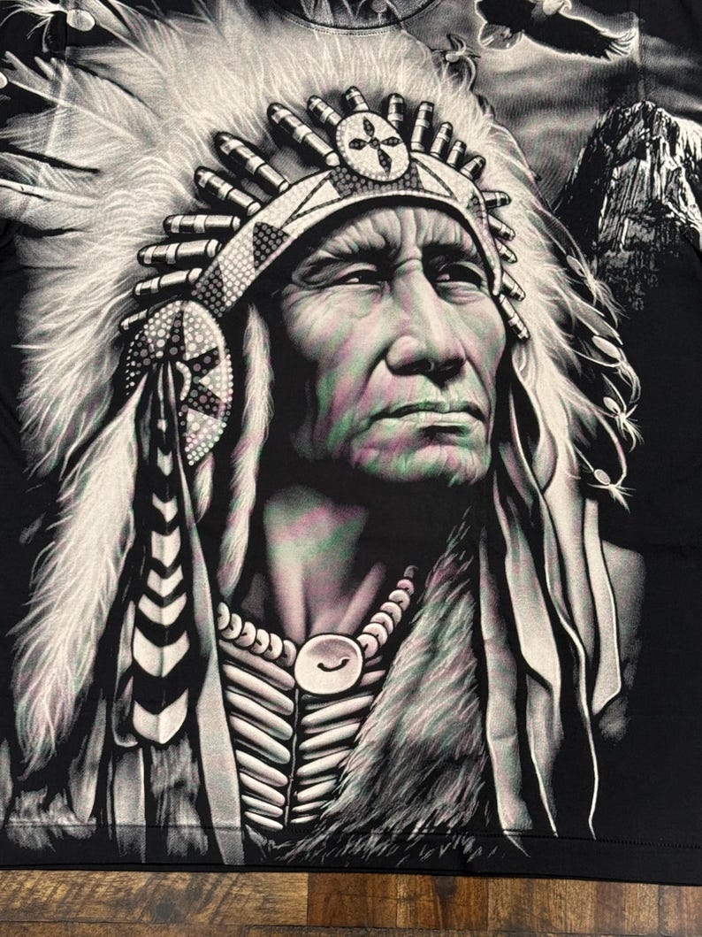 May include: A black and white illustration of a Native American man wearing a headdress with feathers. The man is looking to the right and has a serious expression on his face. The background is a dark gray color.