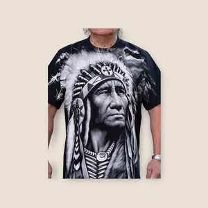 May include: Black and white graphic t-shirt featuring a Native American chief wearing a headdress with feathers. The chief's face is detailed and the background is a blurred image of a cloudy sky.