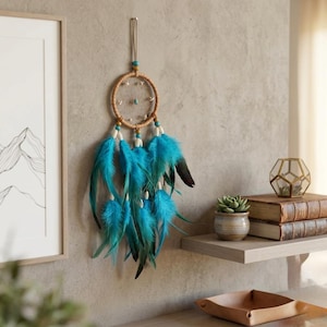 May include: A handcrafted dreamcatcher with a woven circular frame, adorned with turquoise feathers and beads. The dreamcatcher is suspended from a metal hook, adding a touch of bohemian decor to any space. The feathers are a vibrant turquoise color.