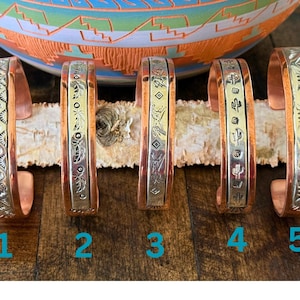 May include: Five copper bracelets with silver inlay designs. Each bracelet has a different design. The bracelets are numbered 1 through 5.