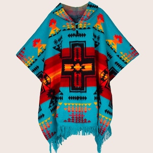 May include: A turquoise poncho with a hood and fringe, featuring a geometric pattern in red, orange, yellow, and black. The design includes a central cross-like motif and various arrow-like shapes. The poncho is made of a woven material.