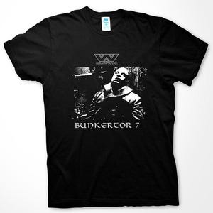 Puede incluir: Camiseta negra con un gráfico blanco de una persona con la cabeza echada hacia atrás y el texto "W:IUMPSCHU: BUNKERTOR 7".