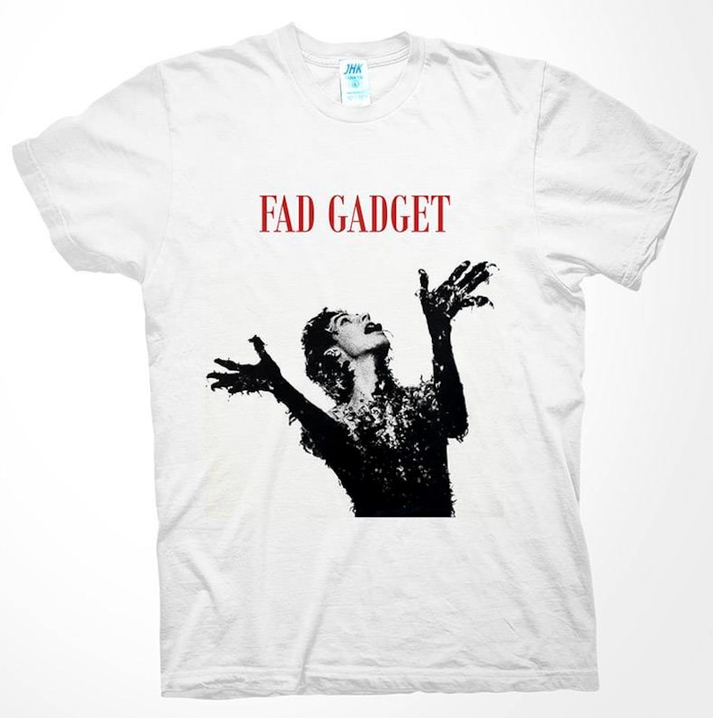 May include: White t-shirt with a black and white image of a person with their arms raised and the text "FAD GADGET" in red letters.