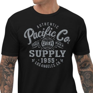 Może przedstawiać: Czarny T-shirt z grafiką w stylu vintage, na której widnieje napis "Authentic Pacific Co. Trade Mark Supply 1955 Los Angeles, CA".