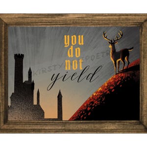 May include: A framed wall art print featuring a silhouette of a castle against a sunset sky, with a deer standing on a red hill. The text "you do not yield" is printed in the center in a combination of bold yellow and black cursive lettering.