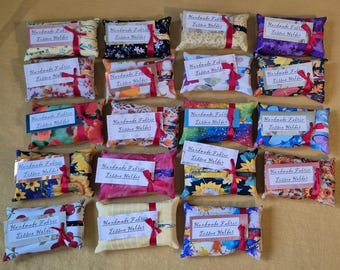 May include: A collection of 18 handmade fabric tissue holders in various colours and patterns. The holders are all rectangular and have a small label that says "Handmade Fabric Tissue Holder".