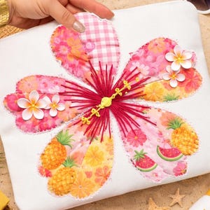 May include: A white fabric pouch featuring a large, colorful flower design. The flower has pink and orange petals with embroidered details, including a red center and yellow accents. Decorative pineapples, watermelons, and white flowers are also included.