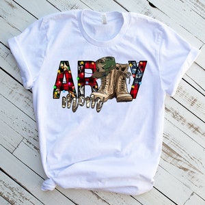 May include: White t-shirt with a red, white, and blue "ARMY" graphic. The letters are decorated with camouflage, Christmas lights, and a pair of military boots.