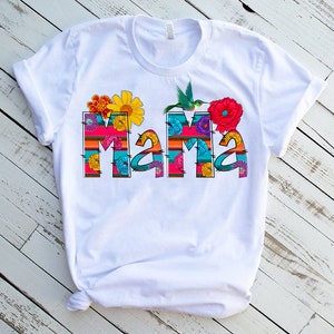 May include: White t-shirt with a colorful floral design that spells out "Mama".