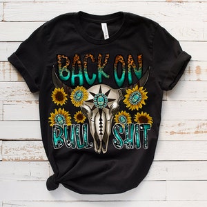 May include: Black t-shirt with a turquoise and white skull design with sunflowers and the text "Back on Bull Shit".
