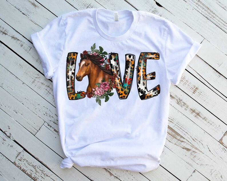 May include: White t-shirt with a graphic of the word "LOVE" in a colorful, animal print design. The letter "L" features a brown horse head with floral accents.
