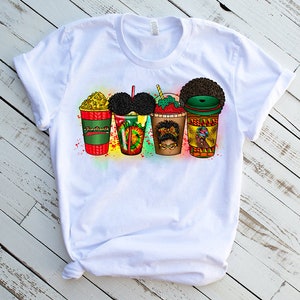 May include: White t-shirt featuring a graphic design of four colourful cups with black hair and faces. The cups are labelled "American", "Soul", "Queen", and "Boss".