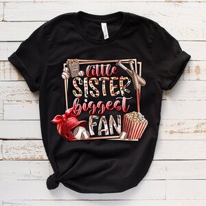 K&ouml;nnte beinhalten: Schwarzes T-Shirt mit einem Grafikdesign im Baseball-Stil. Der Text auf dem Shirt lautet "Little Sister Biggest Fan".