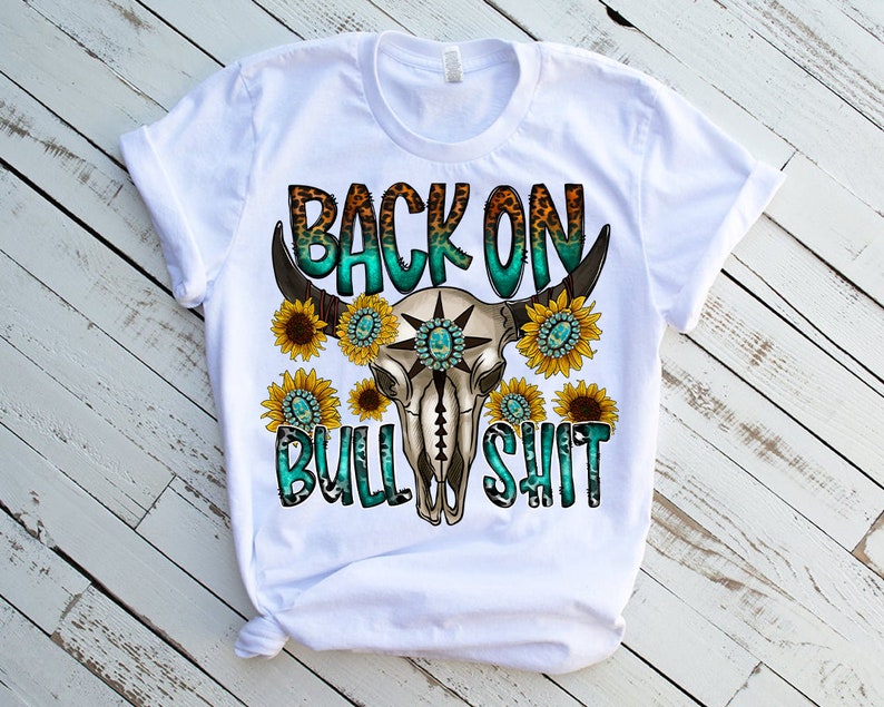 May include: White t-shirt with a turquoise and brown bull skull graphic and the text "Back on Bull Shit" with sunflowers around the skull.