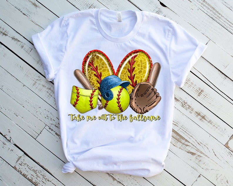 Puede incluir: Camiseta blanca con un dise&ntilde;o de tem&aacute;tica de softbol. El dise&ntilde;o presenta una pelota de softbol, un guante de receptor, un bate y un casco. El texto "Take me out to the ballgame" est&aacute; impreso debajo del dise&ntilde;o.