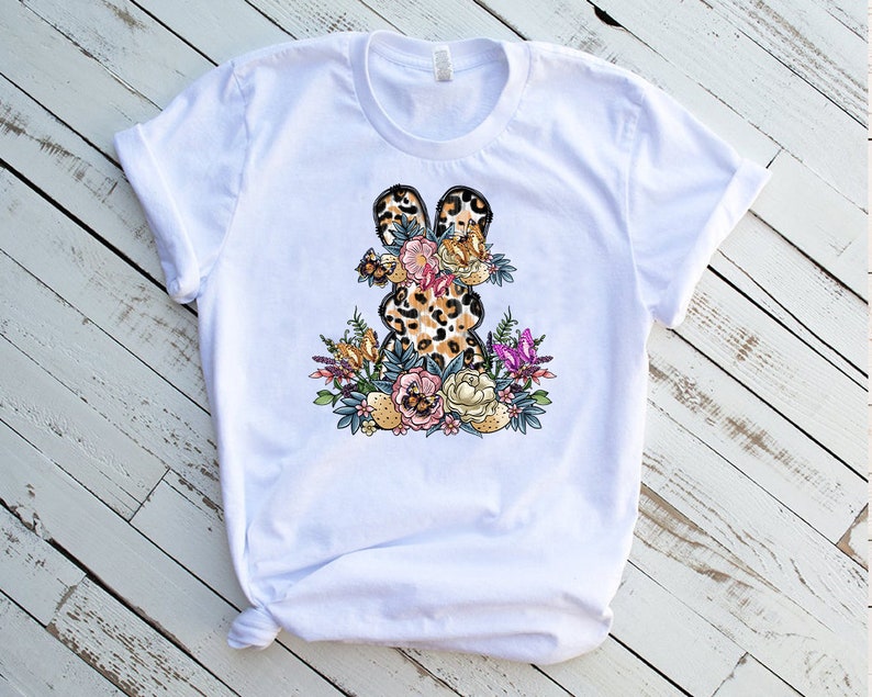 May include: White t-shirt with a graphic of a leopard print bunny surrounded by flowers and butterflies.