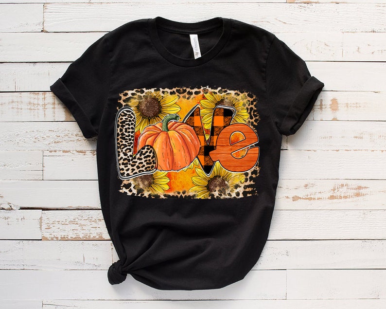 May include: Black t-shirt featuring a graphic design of the word "love" created using pumpkins, sunflowers, and leopard print.
