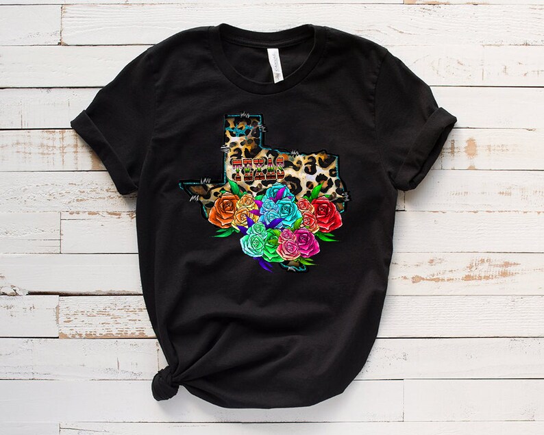 May include: Black t-shirt with a graphic of the state of Texas in leopard print with the words "Texas Strong" inside the outline. The state is surrounded by a colorful bouquet of flowers.