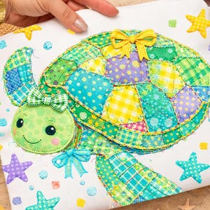 May include: A colorful, patchwork turtle design on a white background. The turtle features a green head with a smiling face and a bow, and a shell made of various patterned fabrics. Starfish and polka dots surround the turtle.