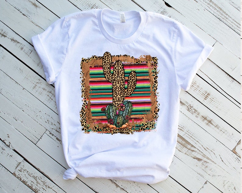 May include: White t-shirt with a graphic of a cactus in a colorful striped pattern with leopard print accents.