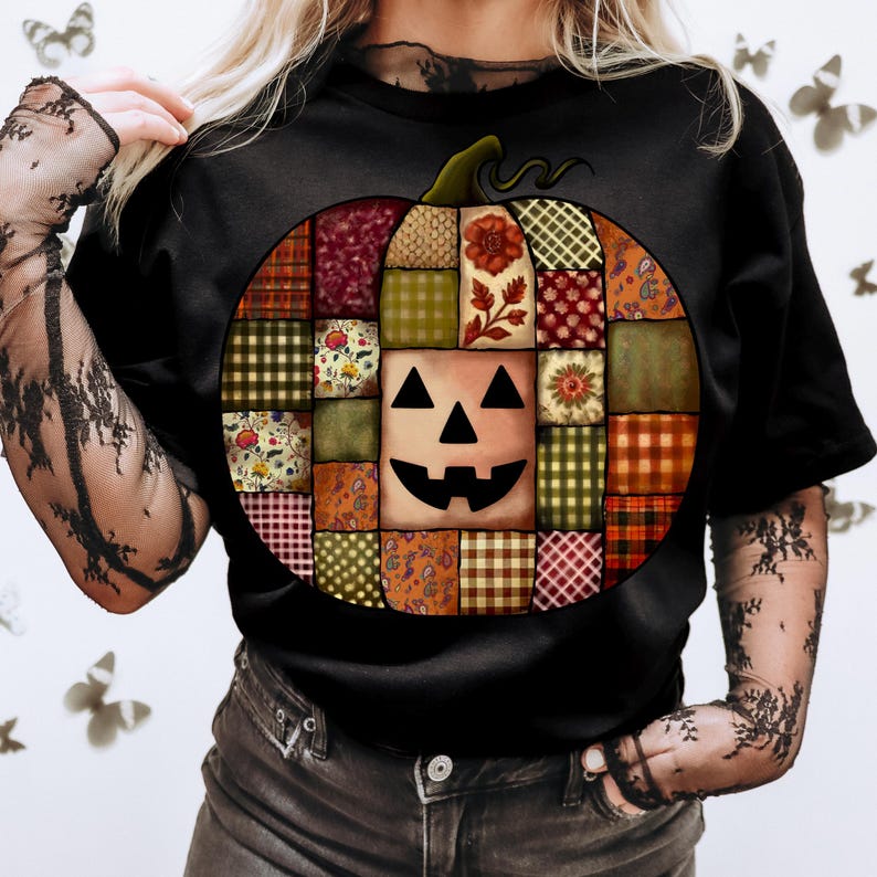 May include: Black t-shirt featuring a patchwork pumpkin design. The pumpkin is composed of various patterned squares in shades of orange, green, red, and brown, with a jack-o'-lantern face in the center. A green stem tops the pumpkin, perfect for Halloween.