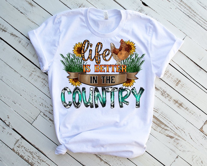 May include: White t-shirt with a graphic design that says "Life is better in the country". The graphic features a chicken, sunflowers, and a green and blue plaid pattern.
