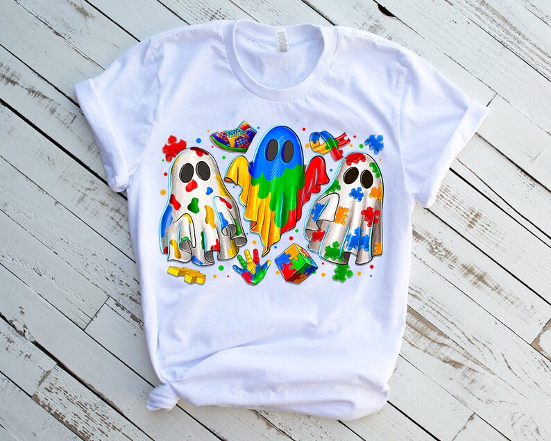 Pode incluir: Camiseta branca com um design colorido de tr&ecirc;s fantasmas com pe&ccedil;as de quebra-cabe&ccedil;a. Os fantasmas usam cores diferentes, incluindo azul, verde, amarelo, vermelho e laranja. O design tamb&eacute;m inclui pe&ccedil;as de quebra-cabe&ccedil;a, uma impress&atilde;o de m&atilde;o e um sapato.