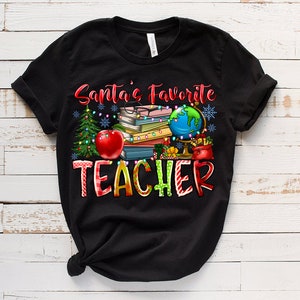 Puede incluir: Una camiseta negra de manga corta con el texto Santa's Favorite TEACHER en letras rojas y multicolores. El gr&aacute;fico incluye una pila de libros, un globo terr&aacute;queo, una manzana roja, un &aacute;rbol de Navidad y luces con copos de nieve.